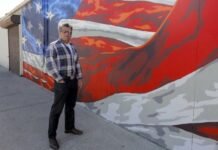 Scott LoBaido artist posing beside his American flag mural artwork