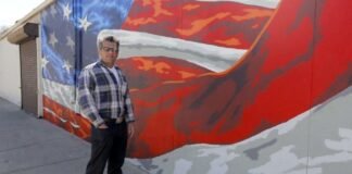 Scott LoBaido artist posing beside his American flag mural artwork